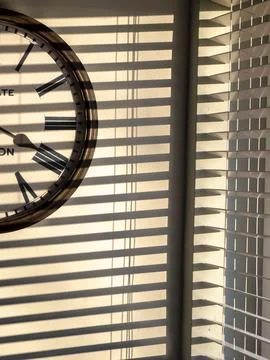 Sunlight patterns on a wall with a clock. 스톡 사진