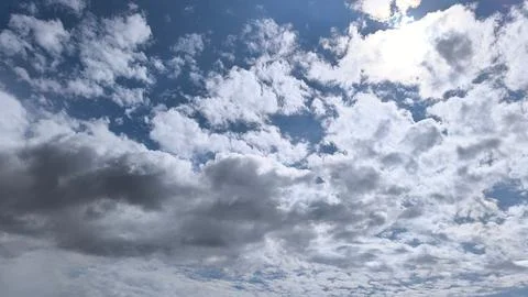 Sunlight peeks through drifting clouds in sky. Stock Photos