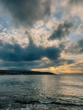 Sunlight piercing stormy clouds casting golden glow over seaside settlement Stock Photos