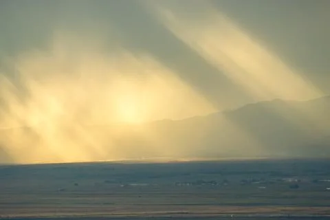 Sunlight rays breaking through clouds over landscape, perfect for backgrounds Stock Photos