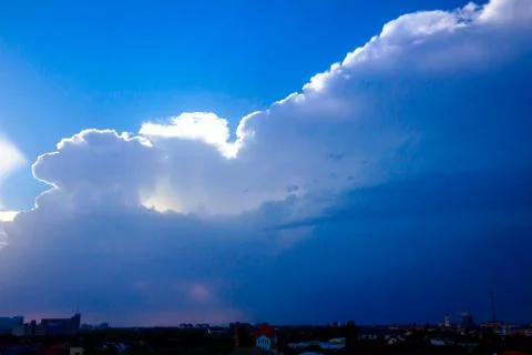 Sunlight rays from the clouds on a blue sky, city in the distance Stock Photos