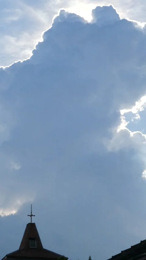 Sunlight rays emerging from behind a large cloud mass above a church spire,.. Stock Footage 345198397