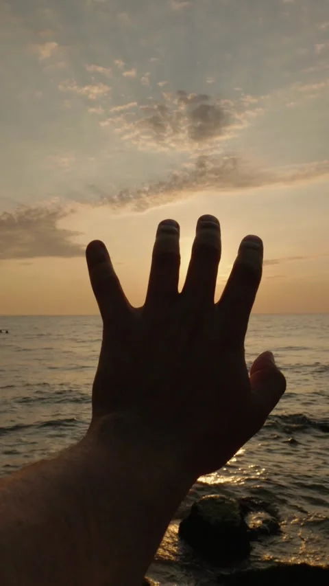 Sunlight rays piercing through fingers of hand reaching out to capture the .. Stock Footage 334913353