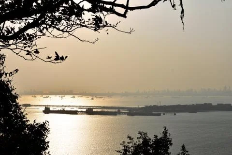 Sunlight reflected in the ocean during sunset near a port Stock Photos