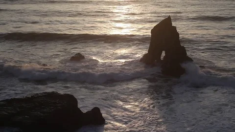 Sunlight reflected on waves by a rocky arch on the northern California coast Stock Footage 76597202