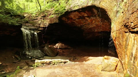 Sunlight reflecting off of a beautiful cave and waterfall Stock Footage 153874650