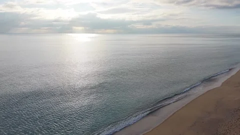 Sunlight reflecting on calm sea surface under dramatic cloudy sky Stock Footage 327840355