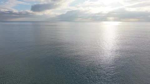 Sunlight reflecting on calm sea surface under dramatic cloudy sky Stock Footage 327840359