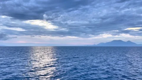 Sunlight Reflecting on Ocean Surface Beneath Dramatic Cloudy Sky Stock Footage 335921134