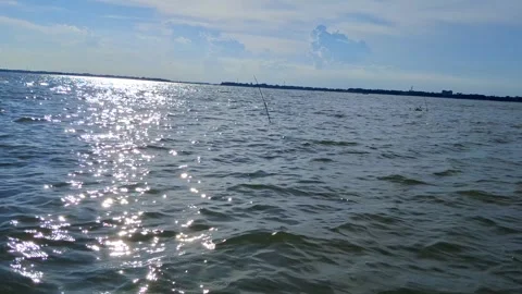 Sunlight reflecting on rippling water surface with fishing rods Vídeo Stock 331807070