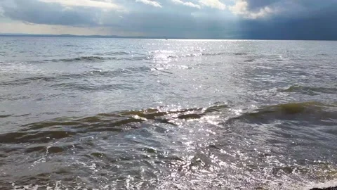 Sunlight reflecting on sea waves with dramatic clouds at horizon. Stock Footage 330088817
