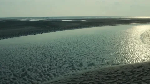 Sunlight Reflecting on Shallow Water Along a Sandy Beach at Low Tide Stock Footage 239170834