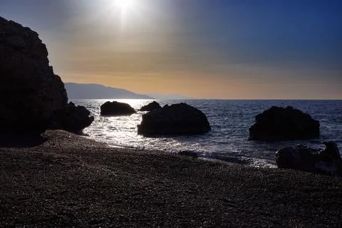 Sunlight reflecting on water at pebble beach sunset Stock Photos