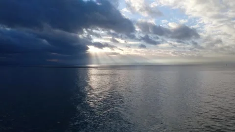 Sunlight Reflection Across Open Ocean Beneath Heavy Cloudy Sky Stock Footage 343997549