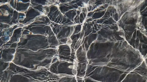 Sunlight reflections on dark rippling water surface Stock-Footage 312902336