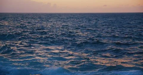 Sunlight reflections on the rippling ocean water during sunset. Stock Photos