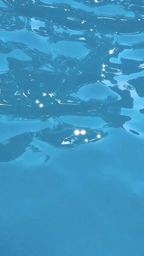 Sunlight reflections shimmer across a clear blue water surface with gentle Stock Footage 346649055