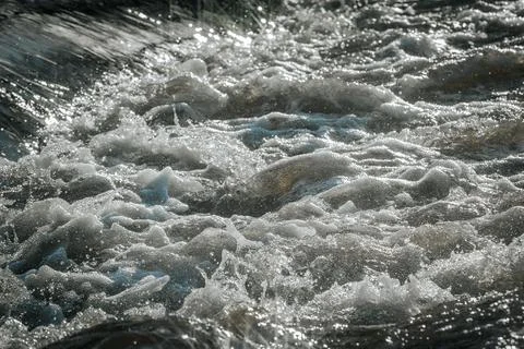 Sunlight reflects off flowing water, creating a dazzling starburst effect. Stock Photos