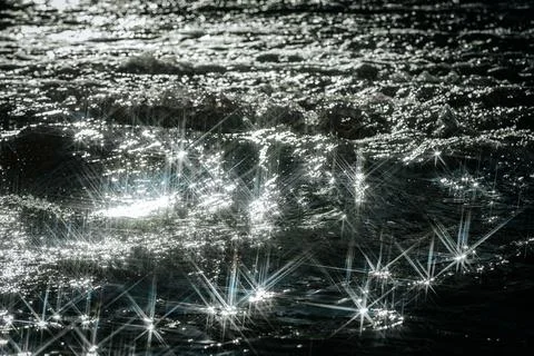 Sunlight reflects off flowing water, creating a dazzling starburst effect. Stock Photos