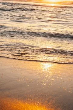 Sunlight reflects on ocean waves at sunset creating a warm glow on the water' Stock Photos