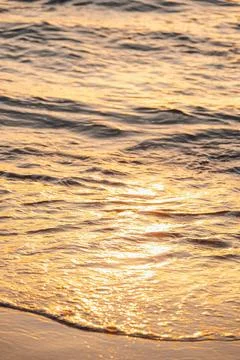 Sunlight reflects on ocean waves at sunset creating a warm glow on the water' Stock Photos