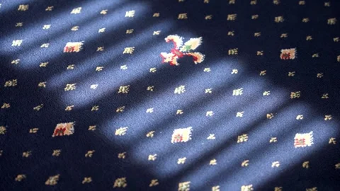 Sunlight shadow moving across patterned blue carpet Stock Footage 334942970