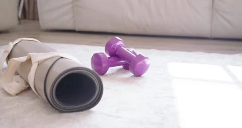 Sunlight is shifting, causing patch while gray mat, strap and purple dumbbells Stock Footage 337288184