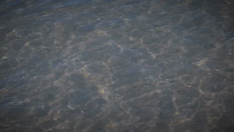 Sunlight shimmers in surf waves in the shallow sea, sand can be seen through Stock Footage 96079117