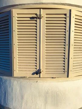 Sunlight shines on a closed window shutter on a building in the late afternoo Фото