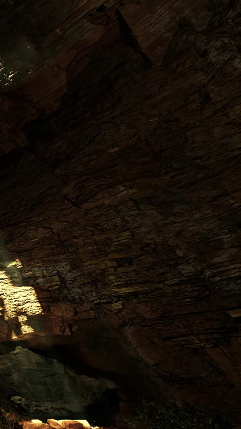 Sunlight shines on rocky cave wall in dark underground environment Stock Footage 341984132