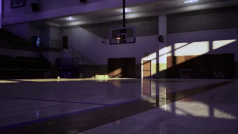Sunlight shines on smooth gym floor with distant hoop silhouette Stock Footage 341825366