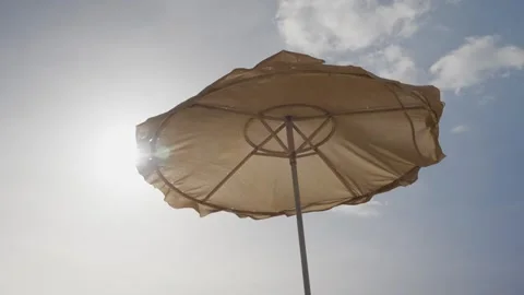 Sunlight shines through a weathered beach umbrella Stock Footage 337033888