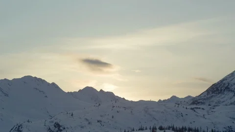 Sunlight shining over a snowy mountain range at sunset Stock Footage 113260045