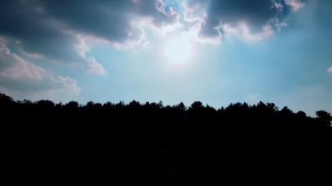 Sunlight Shining Through Clouds Above A Dark Forest Silhouette At Sunset Stock Footage 341946540