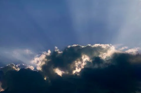 SUNLIGHT SHINING THROUGH CLOUDS CREATING SILVER LINING EFFECT AGAINST BLUE SK Foto stock