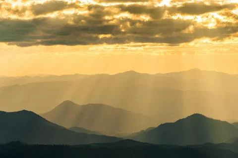 Sunlight shining through clouds onto hazy mountain in Thailand Stock Photos