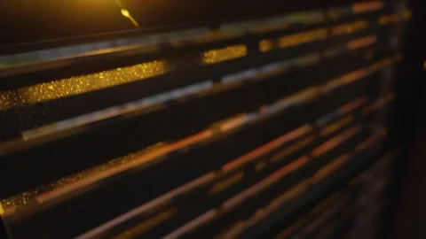 Sunlight shining through the cracks of mechanical window blinds or shutters as Stock Footage 309842957
