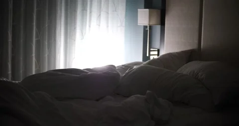 Sunlight shining through curtain over messy bed and hotel room slider shot Vidéo 213383209