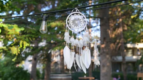 Sunlight shining through a delicate dreamcatcher with white feathers, hanging Stock Footage 285176470