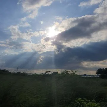 Sunlight Shining Through Dramatic Clouds Over Green Field. Stock Photos