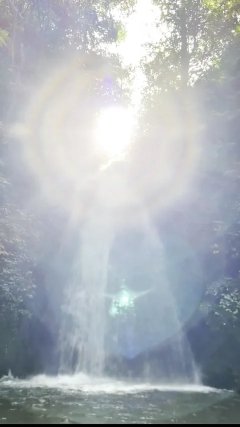 Sunlight shining through a forest waterfall with dramatic lens flare and mist Stock Footage 338392139