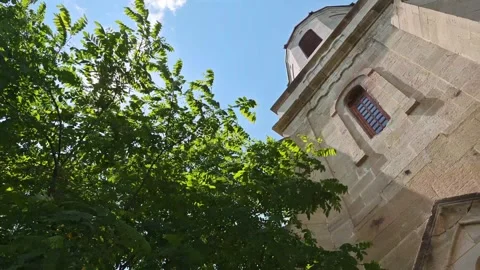 Sunlight shining through green leaves on church tower Vidéo 315357344