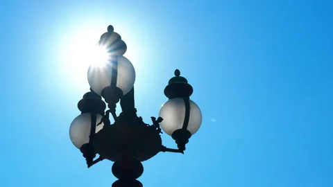 Sunlight shining through a lamppost against blue sky Stock Footage 310385127