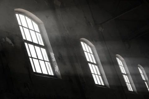 Sunlight shining throuh the windows of an old abandoned industrial warehouse  Stock Photos