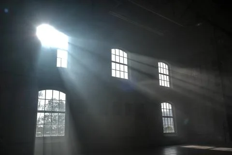 Sunlight shining throuh the windows of an old abandoned industrial warehouse  Stock Photos