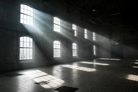 Sunlight shining throuh the windows of an old abandoned industrial warehouse  Stock Photos