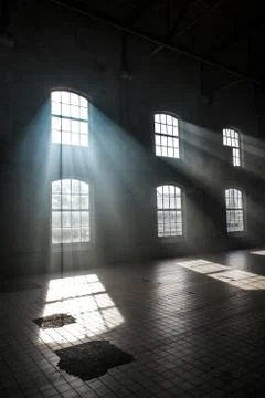 Sunlight shining throuh the windows of an old abandoned industrial warehouse  Stock Photos