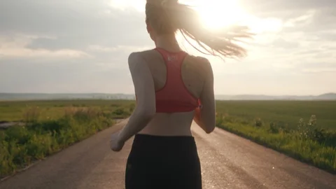 At sunlight shot back runner woman running in road field sunset exercising Stock Footage 112744348