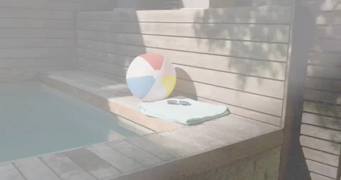 Sunlight sliding slats casting shadows, revealing beachball, towel, shades for Stock Footage 330955373