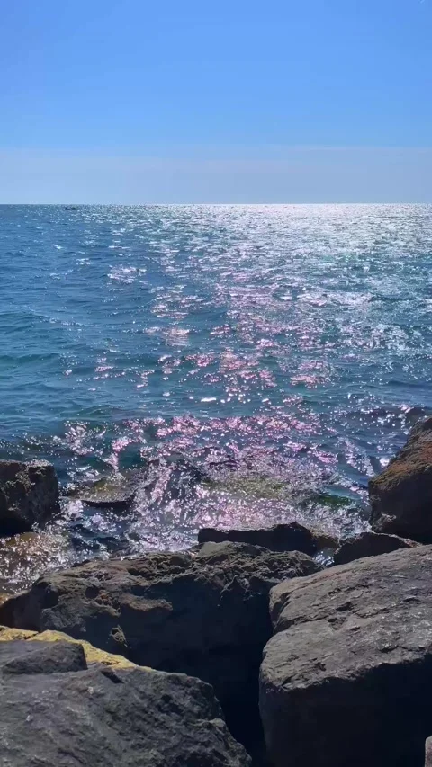 Sunlight Sparkles on Ocean Surface with Rocks in Foreground Stock Footage 310210717